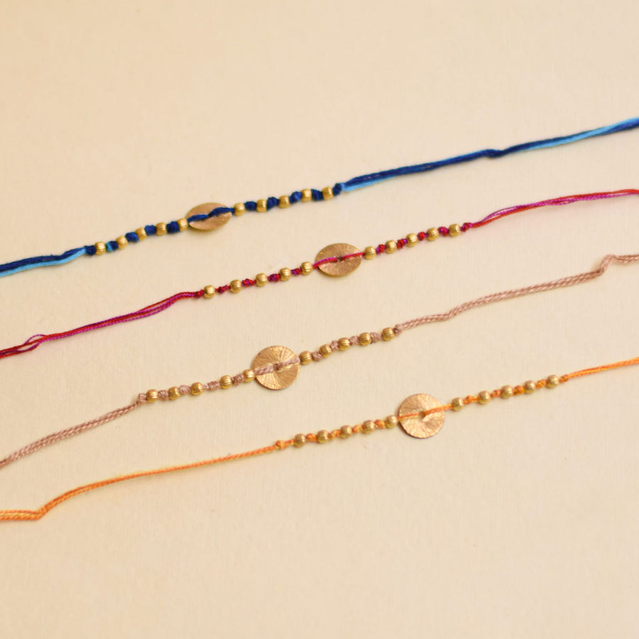 Handmade Swaran Suthra And Pearl Rakhi With Roli Chawal - Four Bracelets Lined Side-by-Side