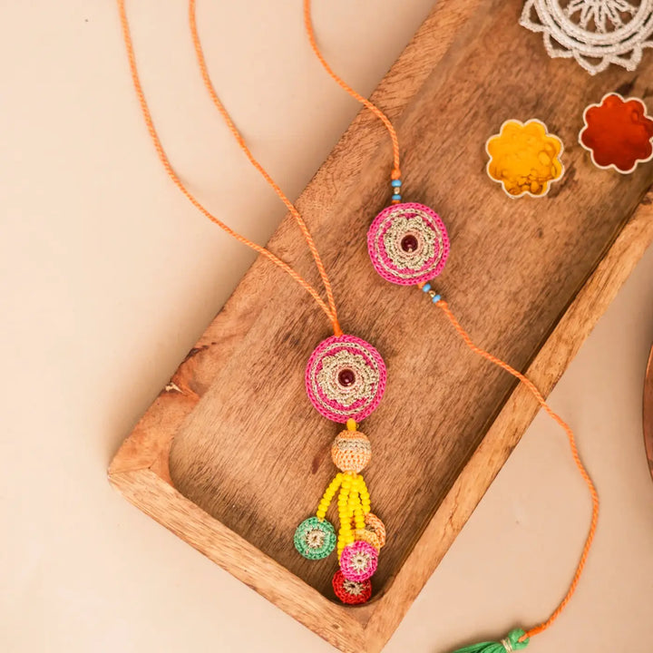 Handmade Crochet Pink Mandala Bhaiya Bhabhi Rakhi With Roli Chawal Set Of 2 - Styled on Wooden Tray with Decor