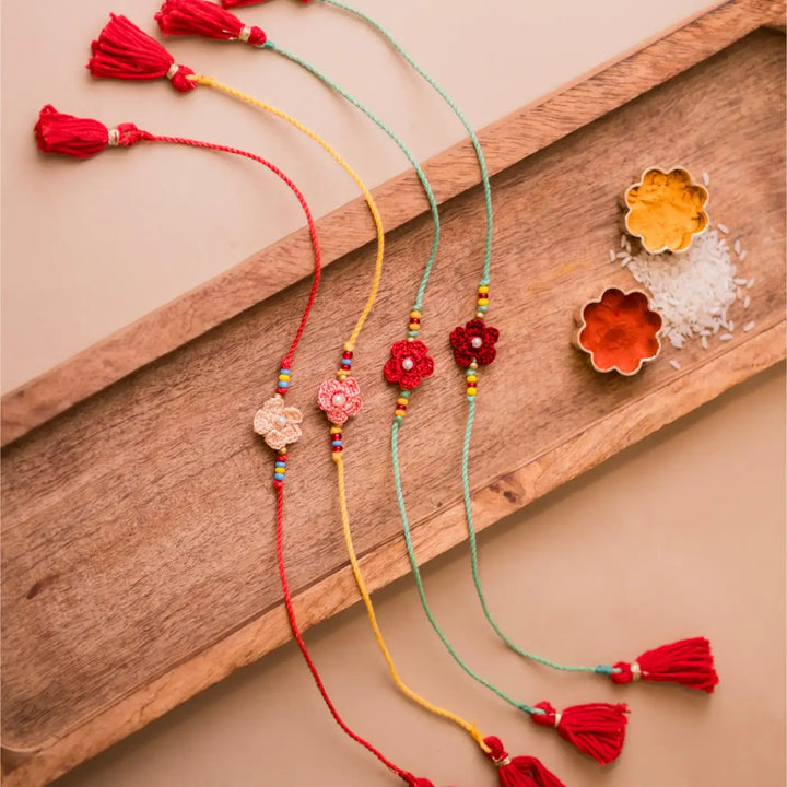 Handmade Crochet Pink Daisies Rakhi With Roli Chawal Set Of 4 - Close-up of red and peach flower bracelets