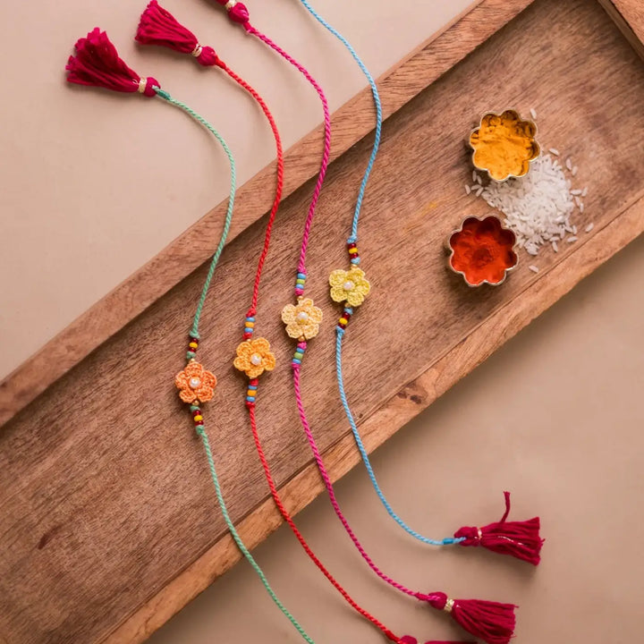 Handmade Crochet Pink Daisies Rakhi With Roli Chawal Set Of 4 - Top view with tassels and spice bowls