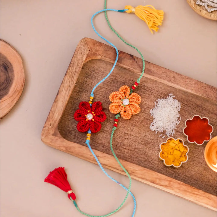 Handmade Crochet Red And Yellow Daffodil Rakhi With Roli Chawal Set Of 2 - Styled on Wooden Tray with Tassels