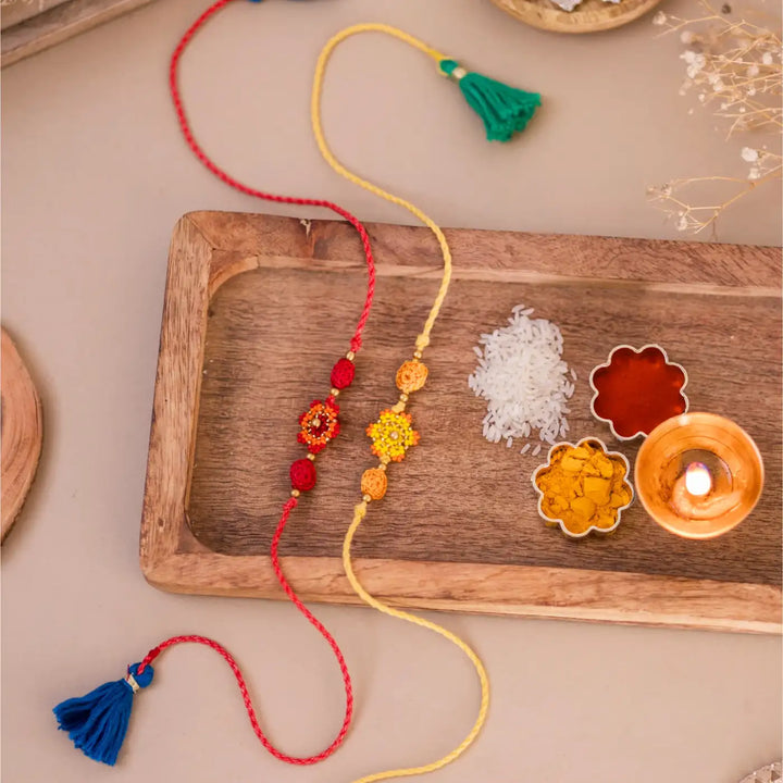 Handmade Crochet Red And Yellow Flower Rakhi With Roli Chawal Set Of 2 - Styled with Cultural Ritual Items
