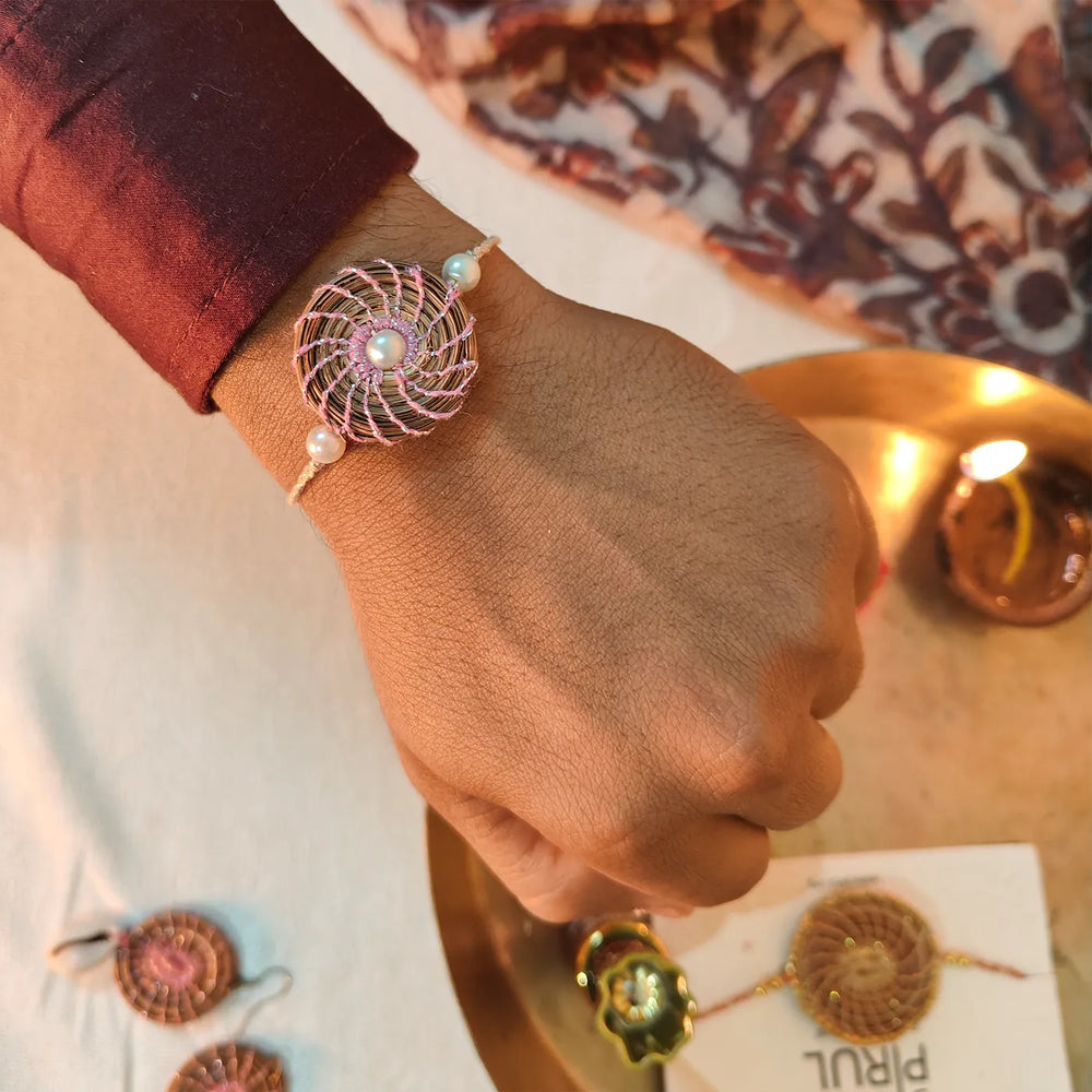 Eco Friendly Handmade Round Pearl Pine Needle Rakhi With Pouch And Roli Chawal - Worn on Wrist with Background