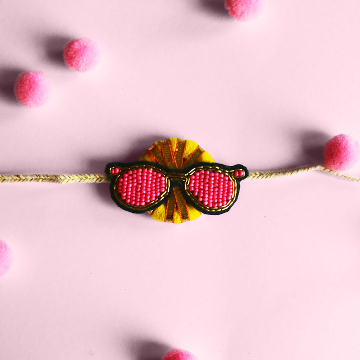 Handmade Reusable Chashma Pom Pom Felt Kids Rakhi - Close-up with Pink Background