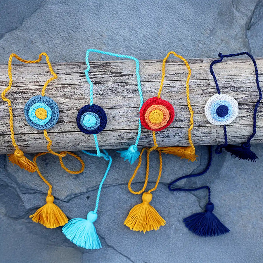 Handmade Crochet Evil Eye Rakhi With Roli Chawal Set Of 4 - Front View on Log