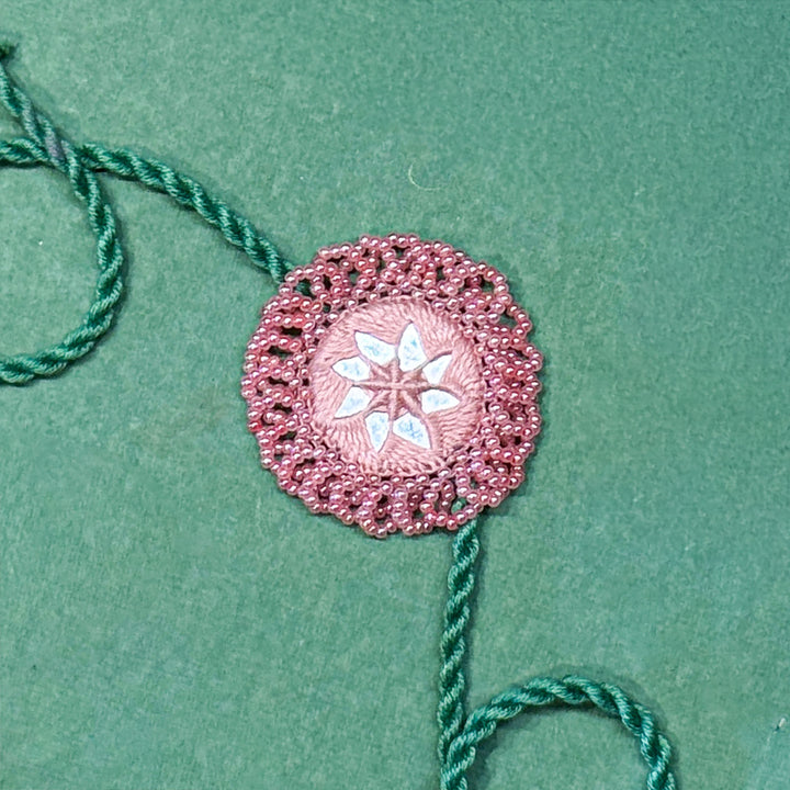 Handmade Reusable Pink And Green Mirror Jhumki Rakhi For Brother - Close-up of Embroidered Centerpiece