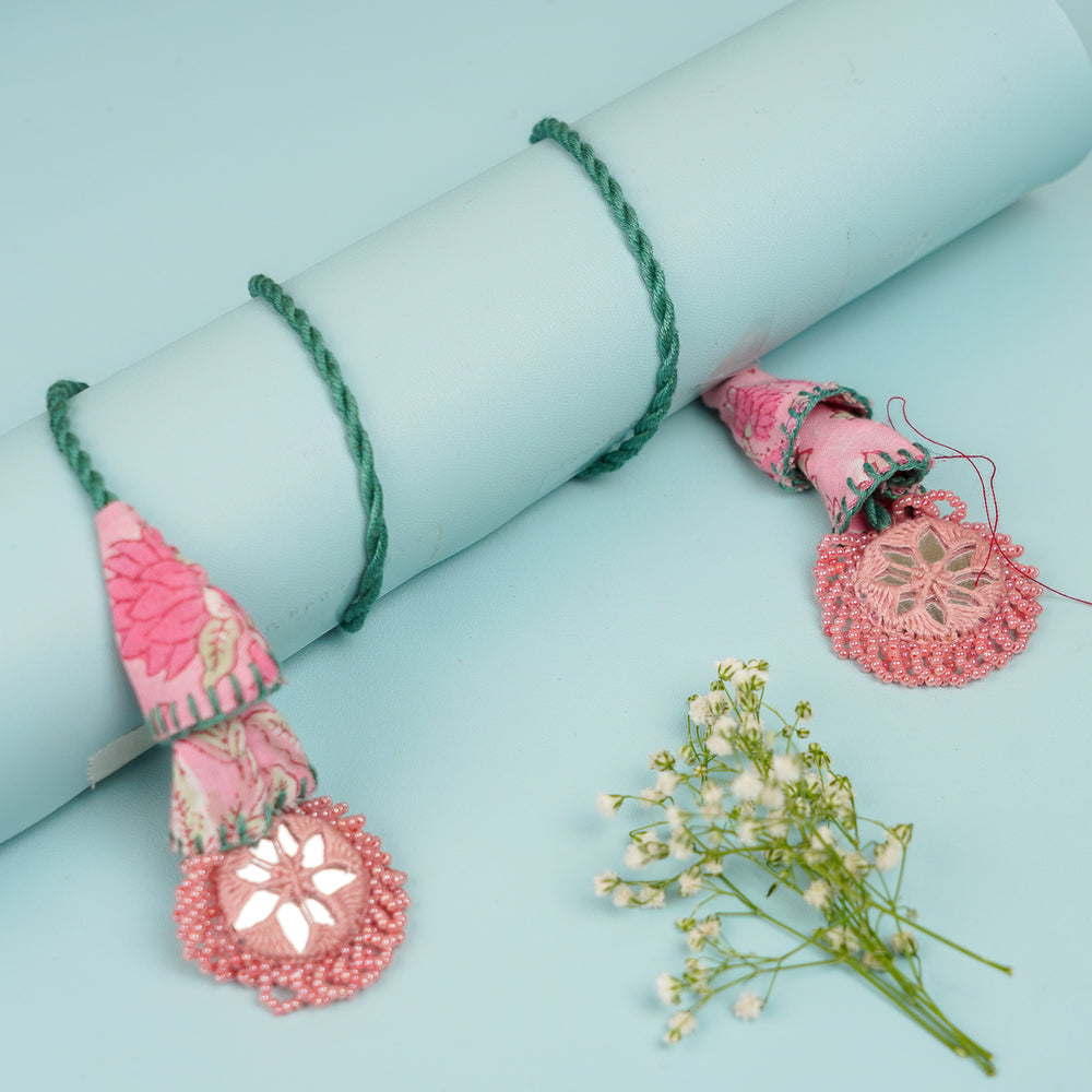 Handmade Reusable Pink And Green Mirror Jhumki Rakhi For Bhaiya And Bhabhi - Wrapped Around Blue Cylinder Display