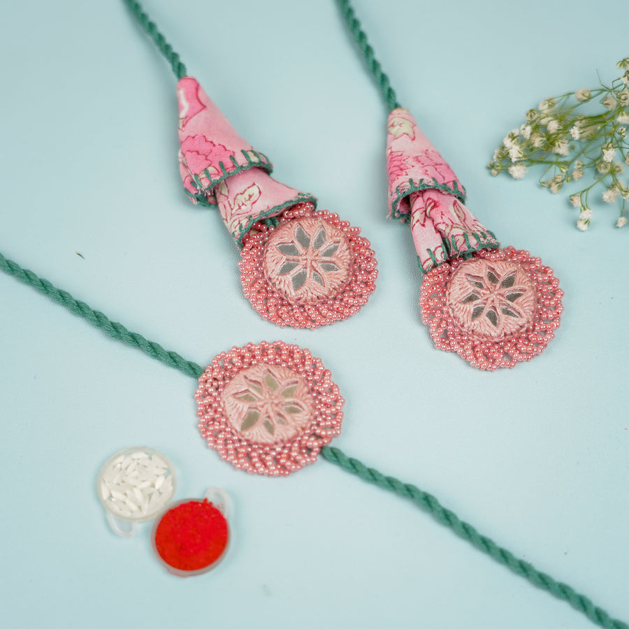 Handmade Reusable Pink And Green Mirror Jhumki Rakhi For Bhaiya And Bhabhi - Flat Lay with Red and White Powder