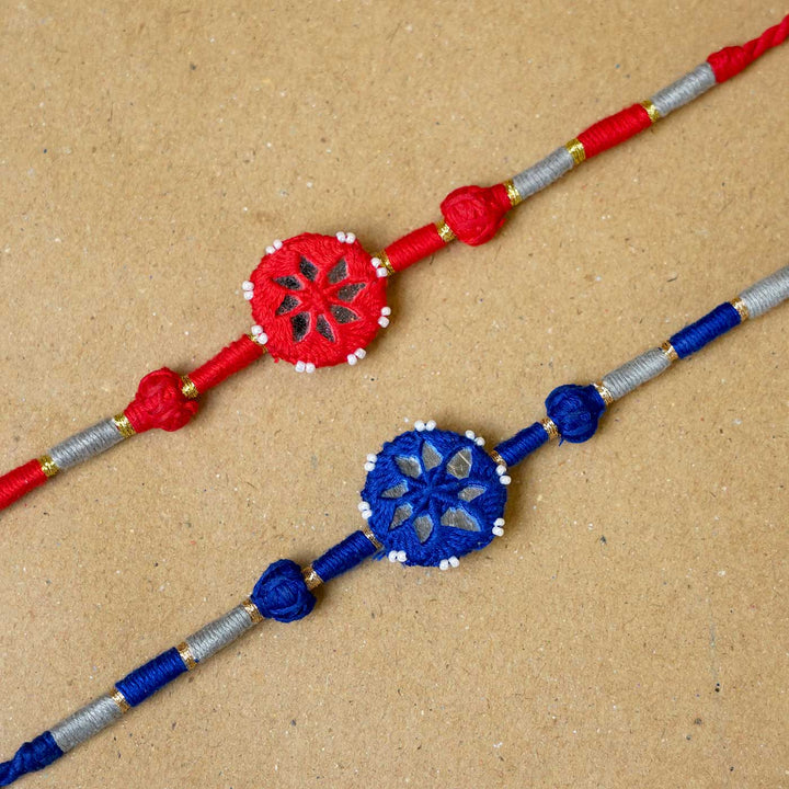 Handmade Mirror Work Patwa Blue Red Cotton Rakhi With Roli Chawal Set Of 2 - Close-up of two rakhis