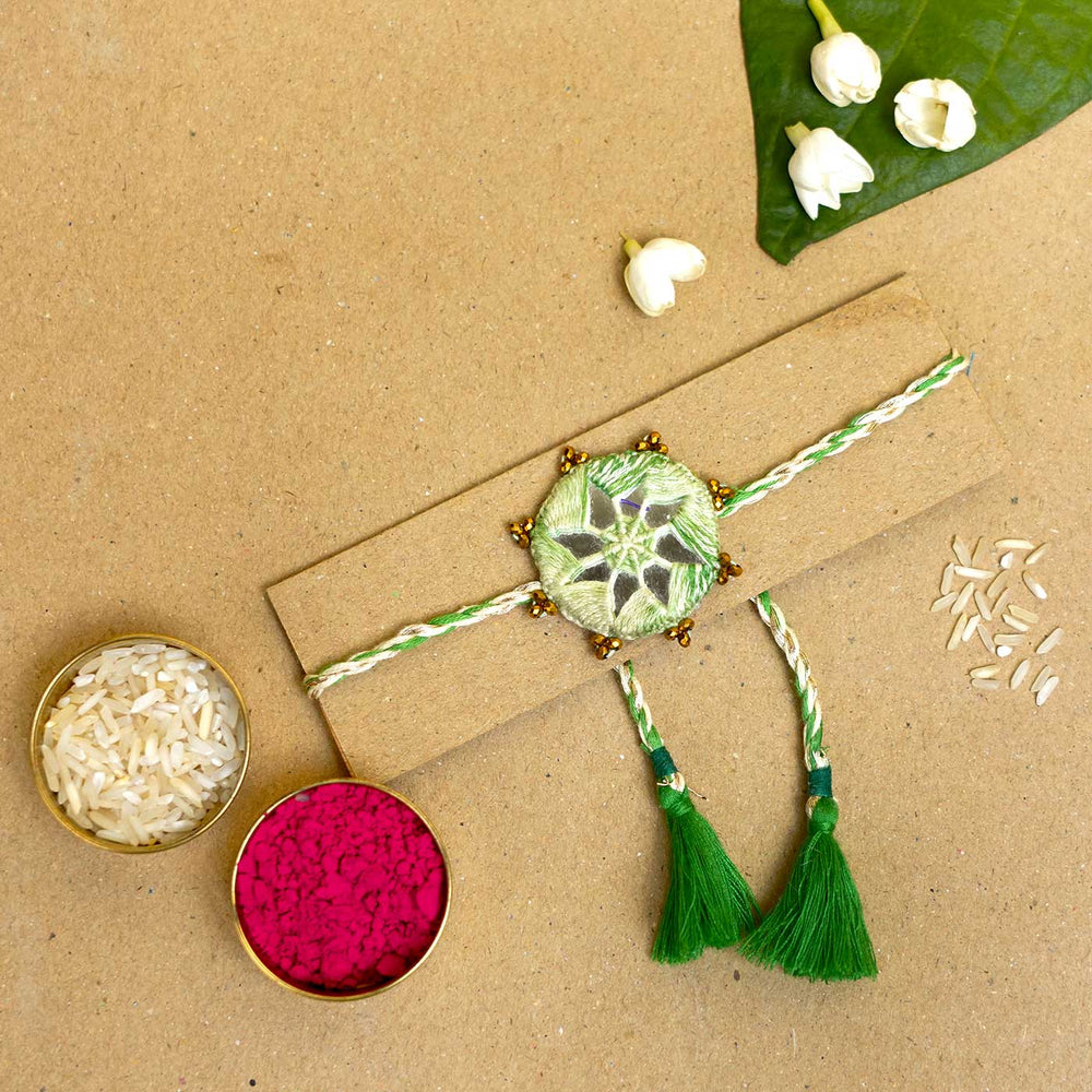 Handmade Mirror Work Kaanha Ombre Green Cotton Rakhi With Roli Chawal - Flat lay with traditional items