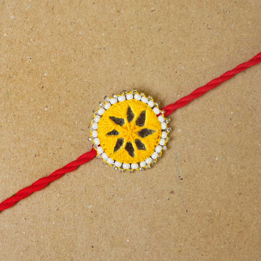 Handmade Mirror Work Kajal Yellow Red Rakhi With Roli Chawal - Close-up of single rakhi
