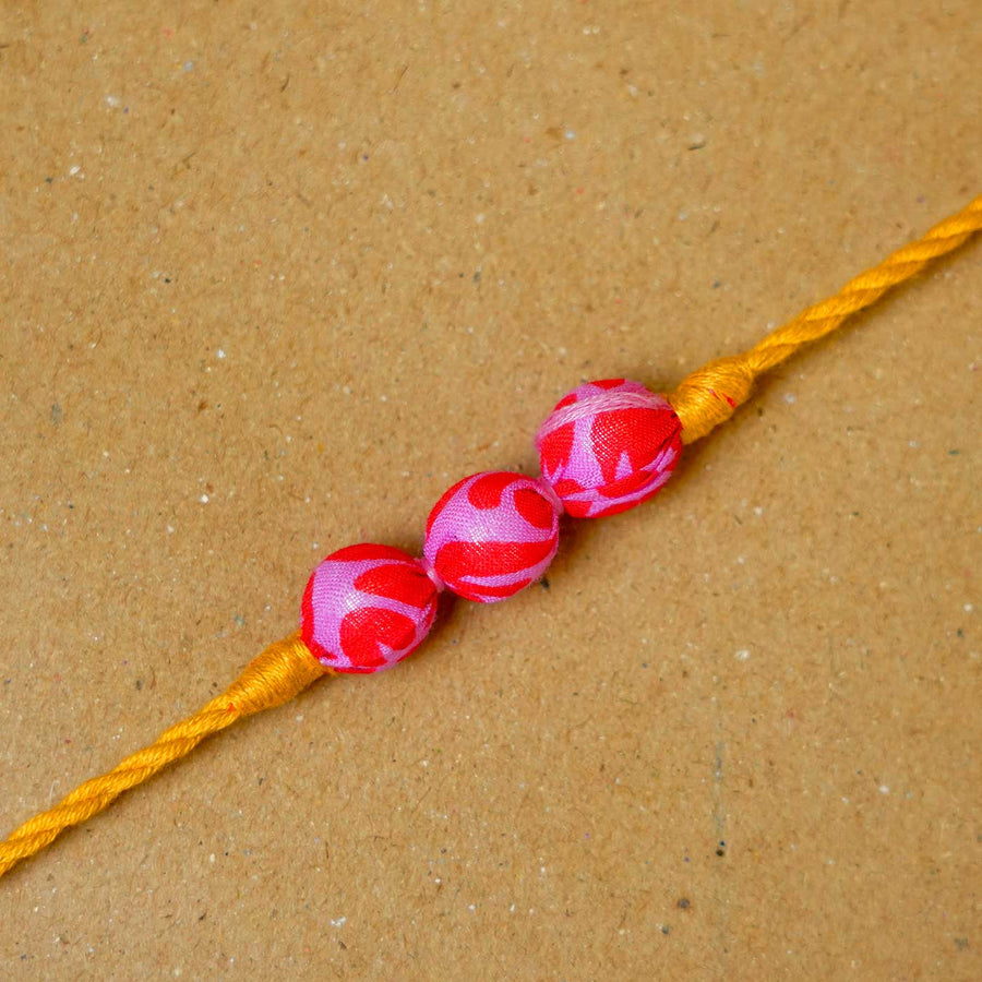 Handmade Pink Yellow Potli Upcycled Fabric Rakhi With Roli Chawal - Close-up of decorative knots