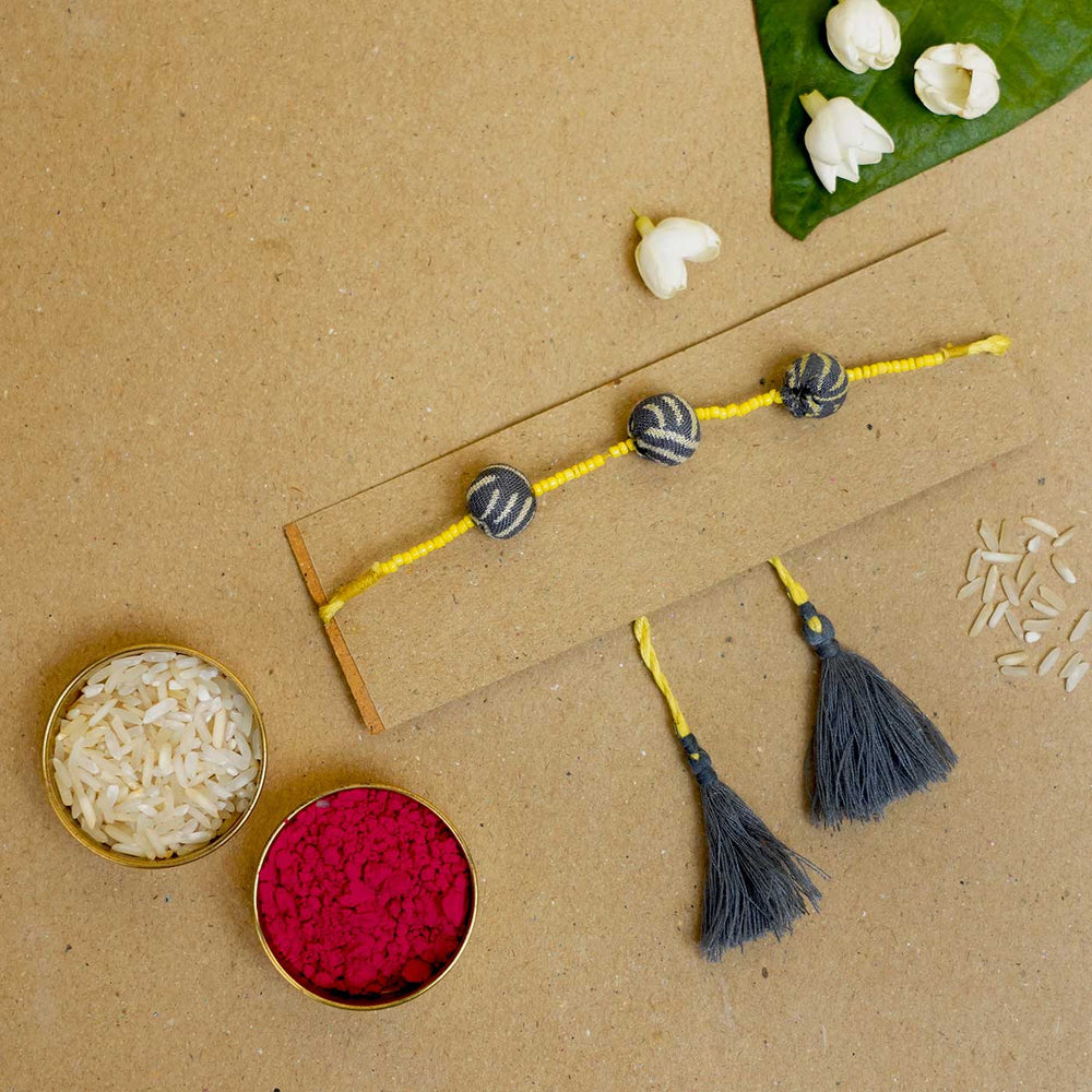 Handmade Swarnamukhi Potli Upcycled Fabric Rakhi With Roli Chawal - Flat lay with color powders and tassels