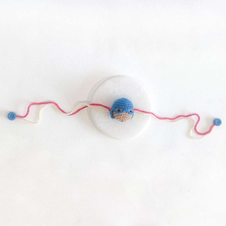 Handmade Crochet Captain America Kids Rakhi With Roli Chawal - Laid Flat on White Surface