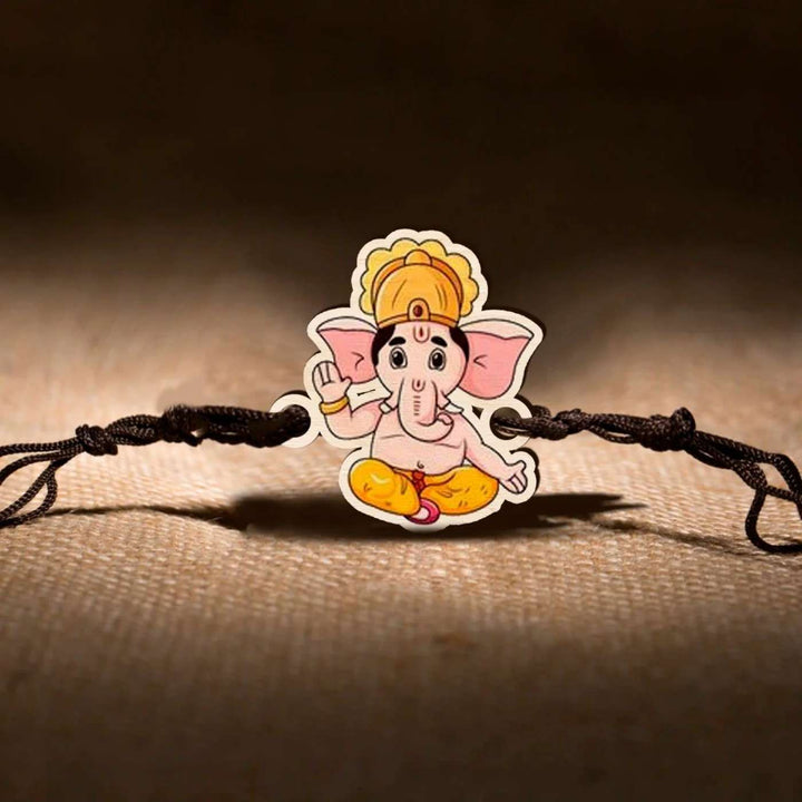 Handmade Ganesha Wooden Rakhi With Roli Chawal - On Fabric Surface Display