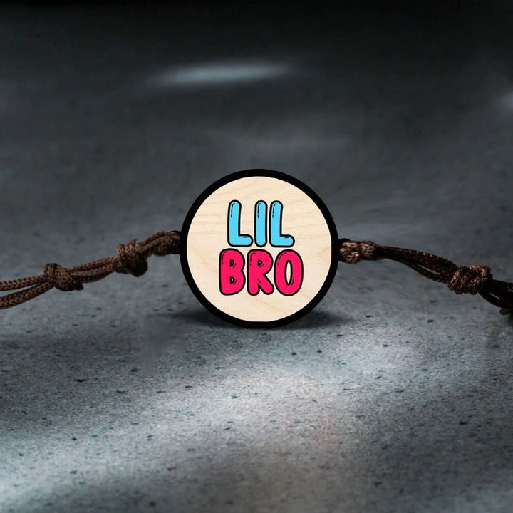 Handmade Little Bro Wooden Rakhi With Roli Chawal - Bracelet front detail on textured surface