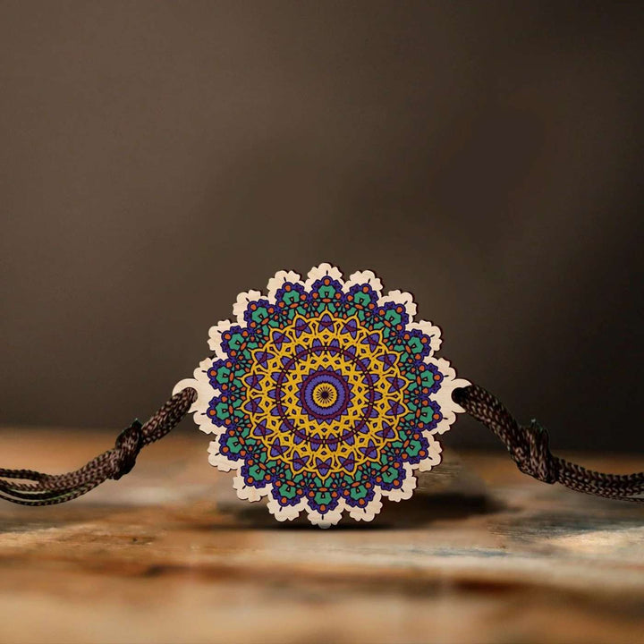 Handmade Mandala Wooden Rakhi With Roli Chawal - Front View on Wooden Surface