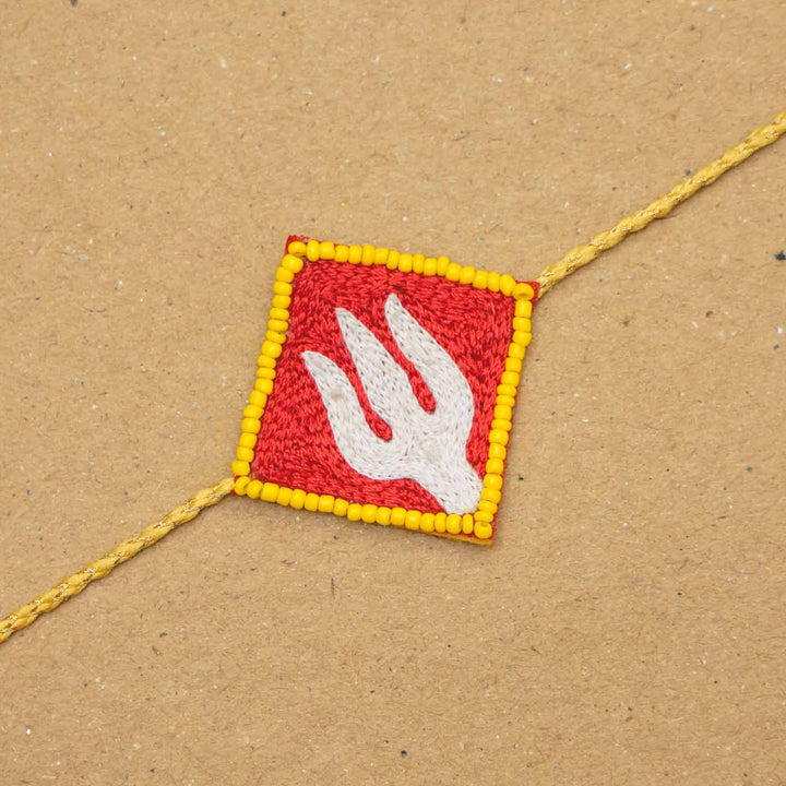 Handmade Beaded Trishul Rakhi With Roli Chawal - Close-up of red trident rakhi