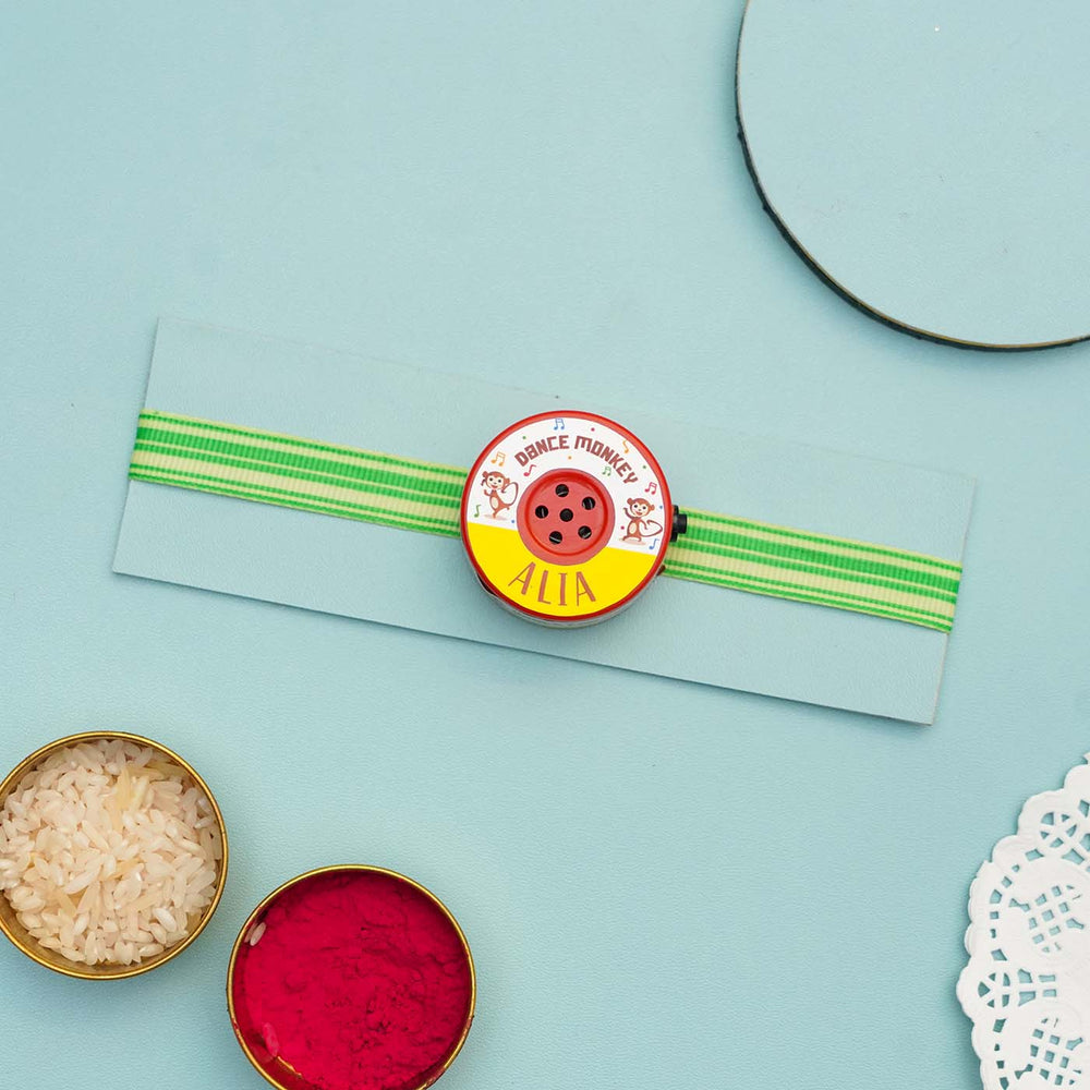 Personalized Musical Dance Monkey Kids Rakhi With Roli Chawal - Flat Lay of Rakhi with Color Bowls
