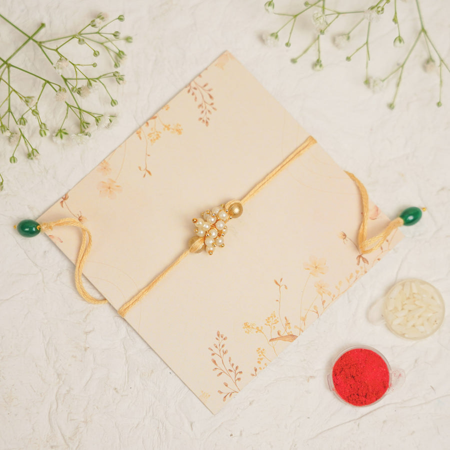 Handmade Single Bajra Ghungroo And Pearl Rakhi With Roli Chawal - Top View with Decorative Elements