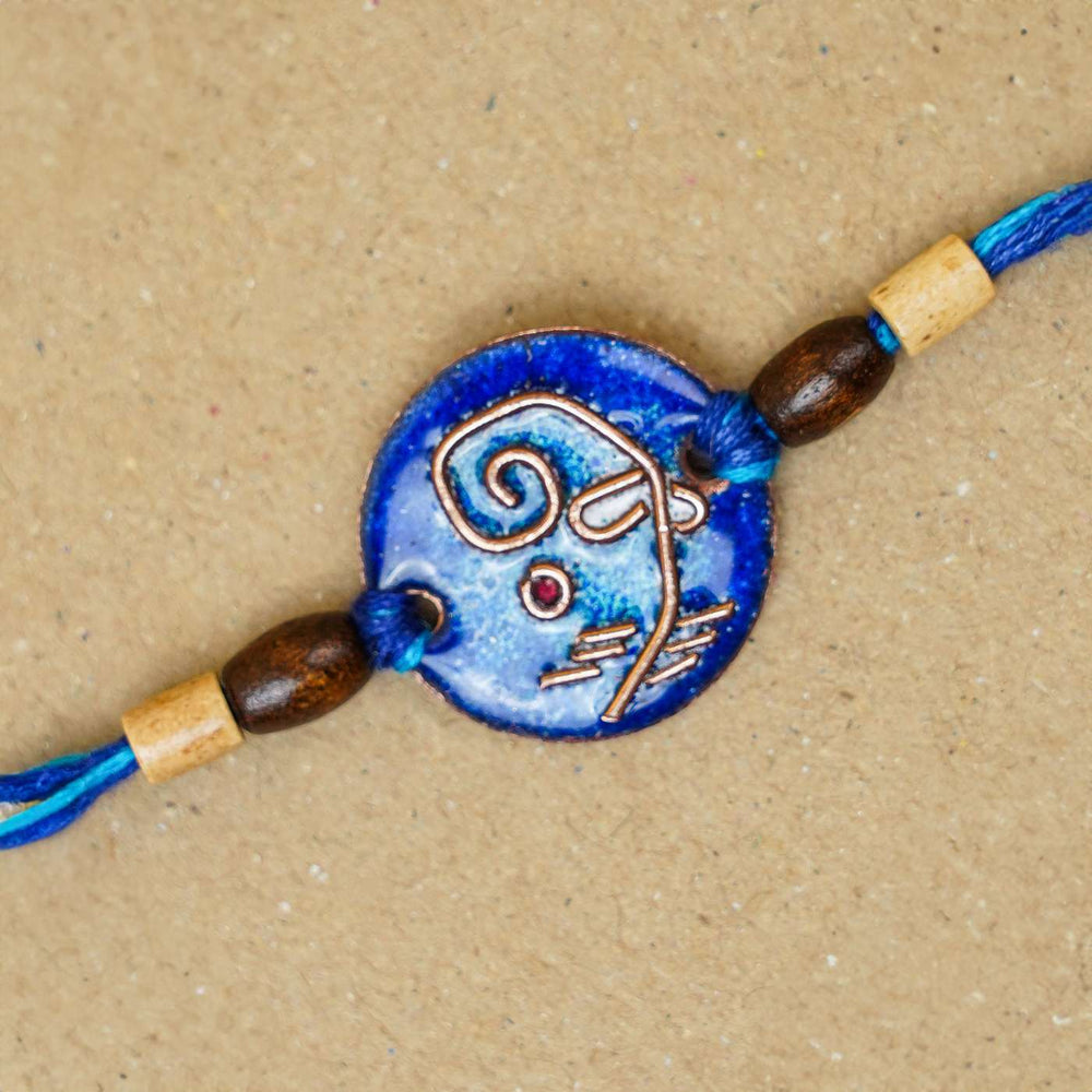 Handmade Round Ganesh Copper Enamel Rakhi With Chocolates And Roli Chawal - Close-up of blue bracelet centerpiece