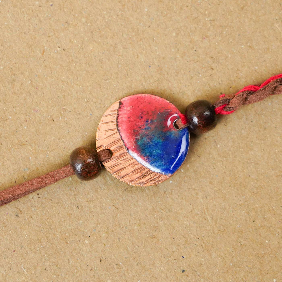 Handmade Rudra Textured Red Copper Enamel Rakhi With Chocolates And Roli Chawal - Close-up of Rakhi centerpiece