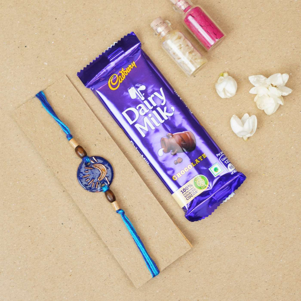 Handmade Chanda Blue Copper Enamel Rakhi With Chocolates And Roli Chawal - Flat Lay with Chocolate and Decor