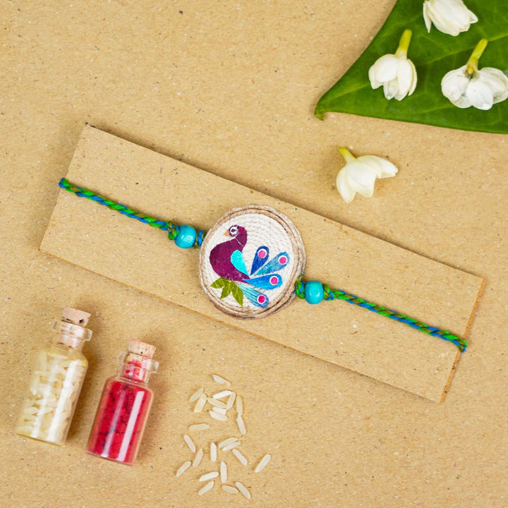 Handmade Pressed Flower Art Peacock Jute Rakhi With Roli Chawal - Bracelet displayed on cardboard holder