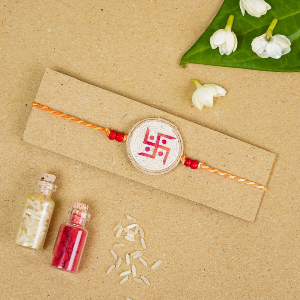 Handmade Pressed Flower Art Swastika Jute Rakhi With Roli Chawal - Flat lay with decorative elements