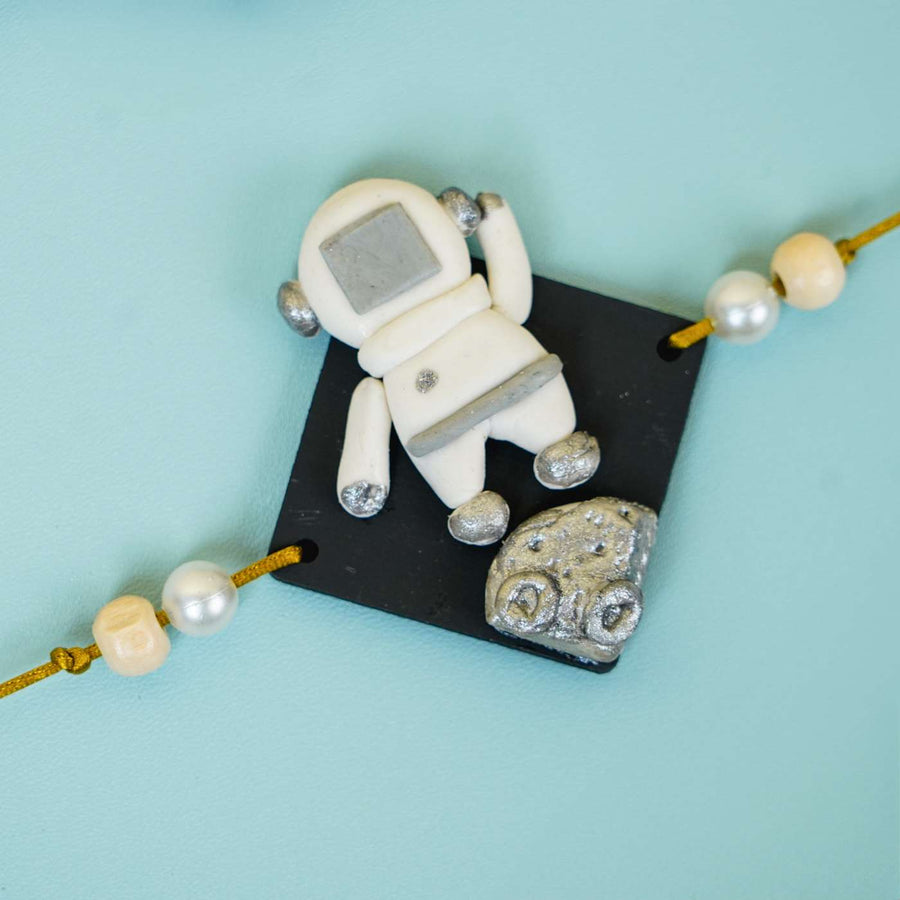 Handmade Miniature Clay Astronaut Kids Rakhi With Roli Chawal - Close-up of Astronaut Charm