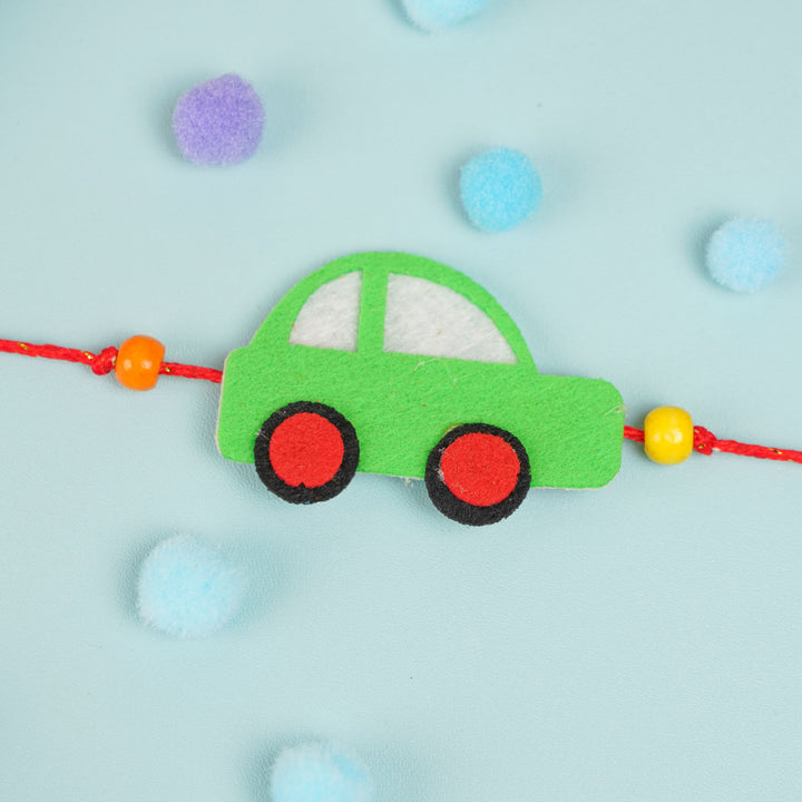 Customized Handmade Beaded Car Theme Pom Pom Felt Rakhi With Roli Chawal For Kids - Side view of green car charm