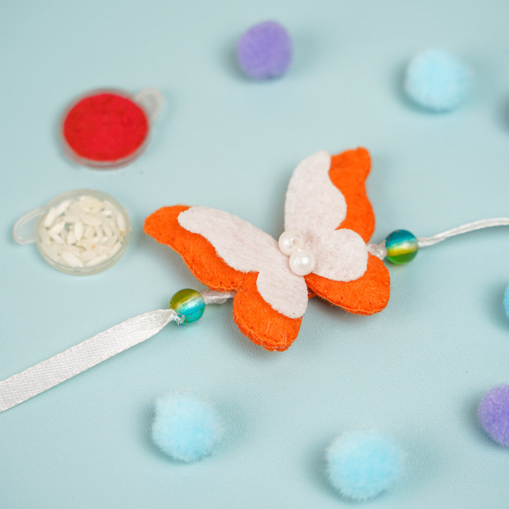 Customized Handmade Beaded Butterfly Theme Pom Pom Felt Rakhi With Roli Chawal For Kids - Angled View with Beads Visible
