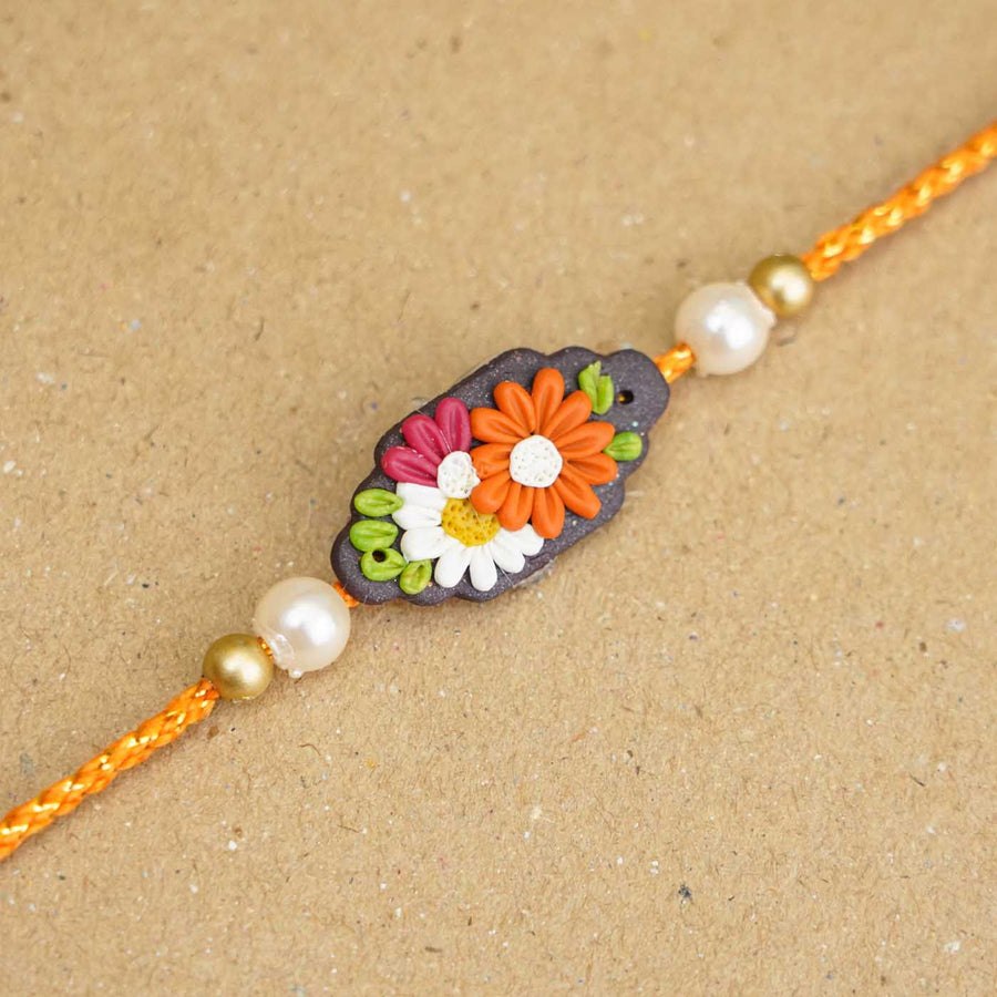 Handmade Miniature Clay Orange And White Floral Rakhi With Roli Chawal - Close-up of Rakhi detail