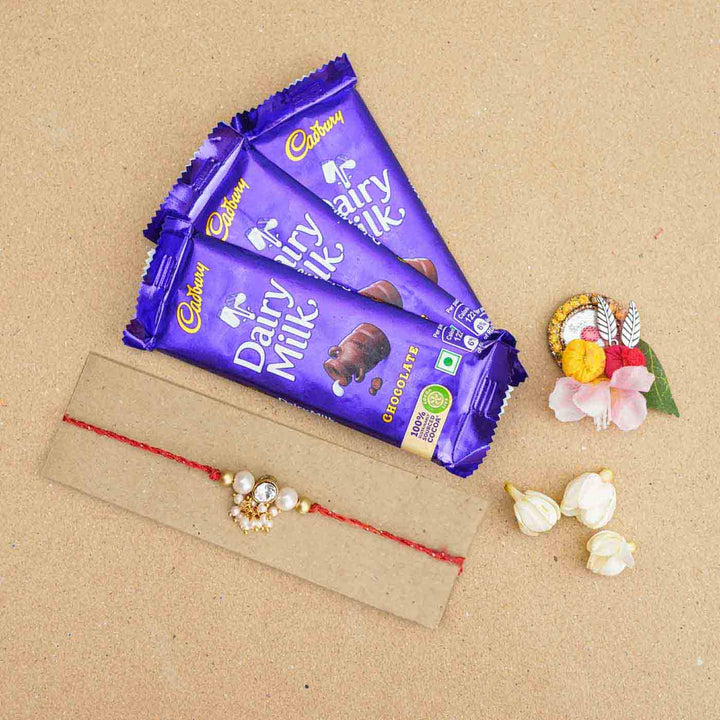Handmade Kundan Red And White Beads Rakhi With Roli Chawal - Flat lay with chocolates and decoration