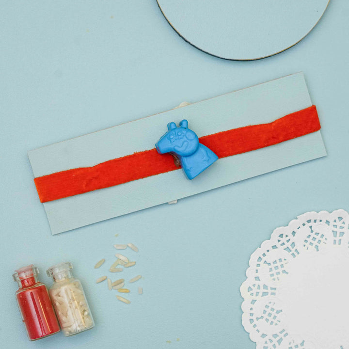 Handmade Peppa Pig Crayon Kids Rakhi With Roli Chawal - Blue clip on red band display with props