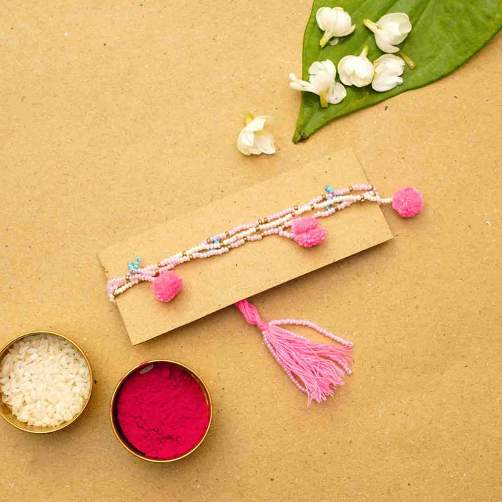 Reusable Beaded Tassel Lumba Rakhi For Bhabhi With Roli Chawal - Bracelet Displayed on Cardboard