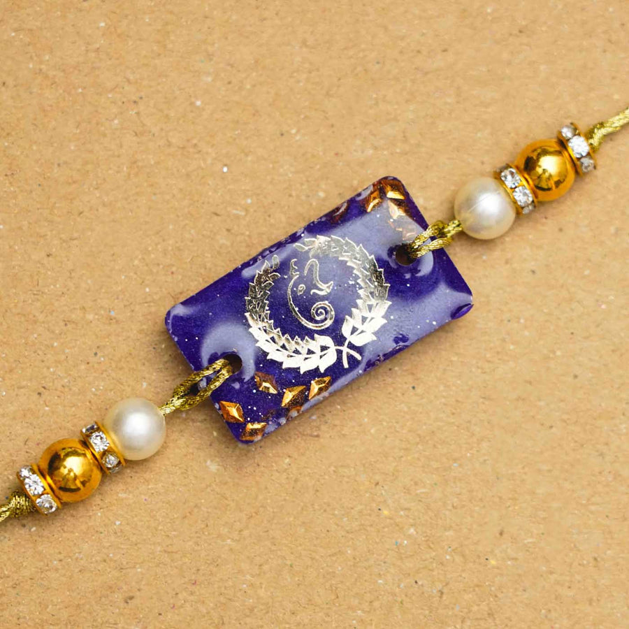 Handmade Resin Plural Ganesha Rakhi With Roli Chawal - Close-up of central emblem