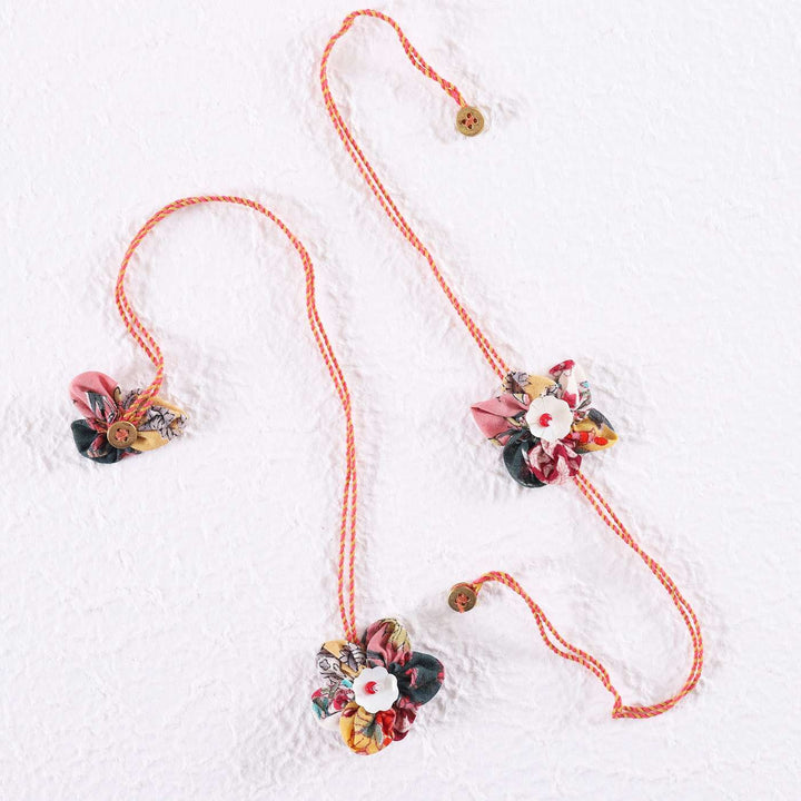 Handmade Fabric Flower Bhaiya Bhabhi Rakhi With Roli Chawal Set Of 2 - Flat Lay on White Textured Surface