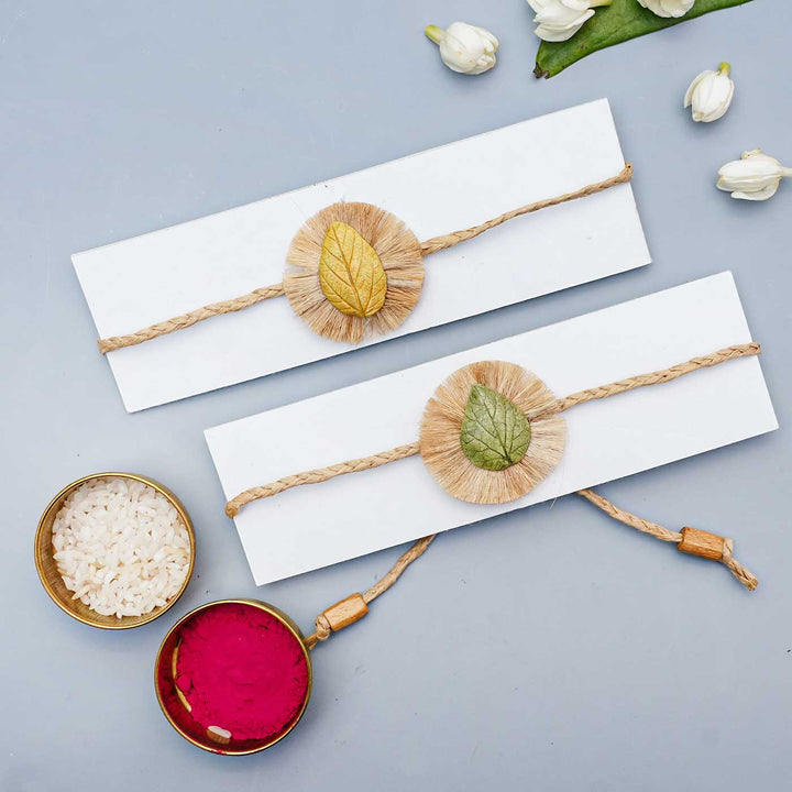 Handmade Papier Mache Yellow And Green Leaf Rakhi With Roli Chawal Set Of 2 - Bracelets on white cards with powders