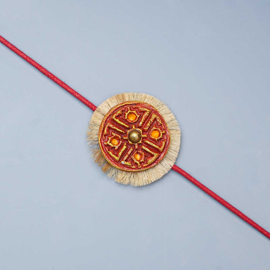 Handmade Papier Mache Swastika With Read Thread Rakhi With Roli Chawal - Close-up of decorative bracelet center