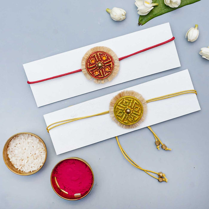 Handmade Papier Mache Red And Yellow Swastika Rakhi With Roli Chawal Set Of 2 - Bracelets displayed on cards