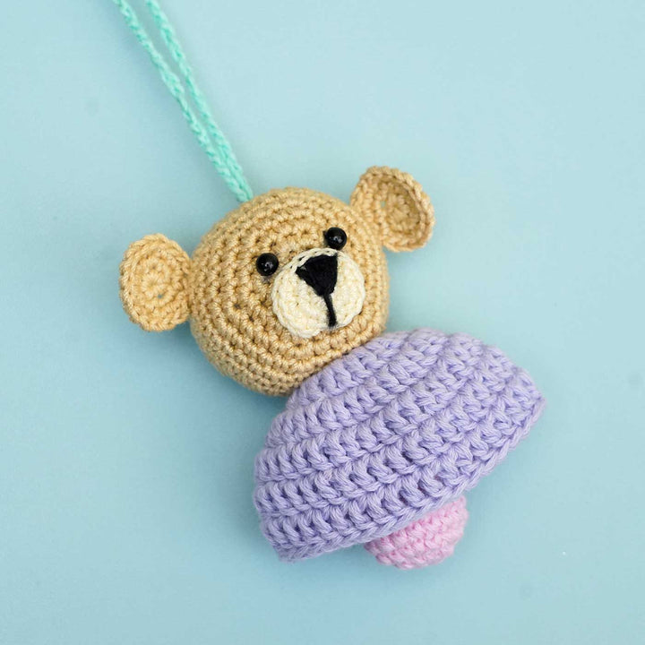 Handmade Crochet Teddy Hug Kids Rakhi With Roli Chawal - Flat Lay Front View on Cardboard