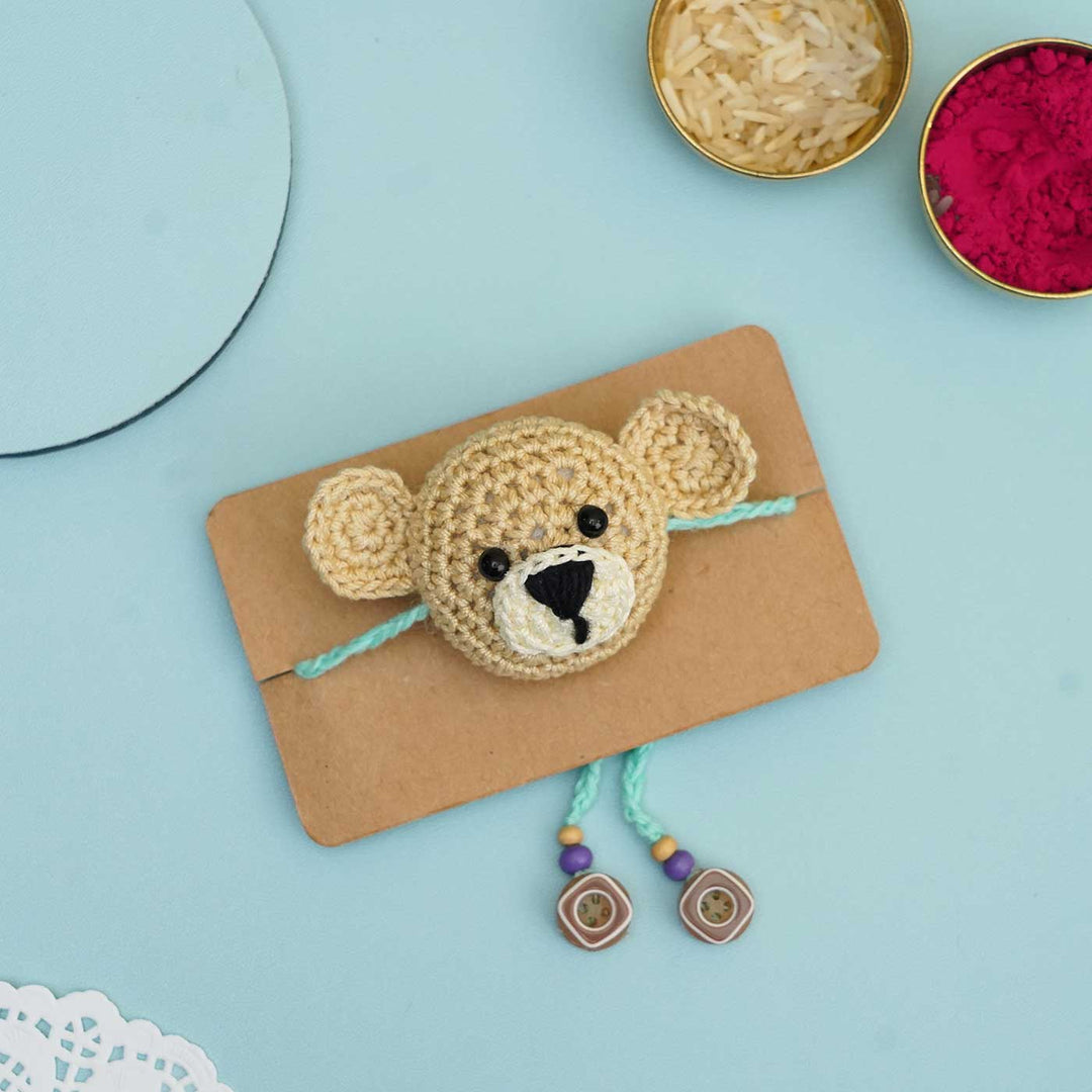 Handmade Crochet Teddy Hug Kids Rakhi With Roli Chawal - Flat Lay on Cardboard Piece