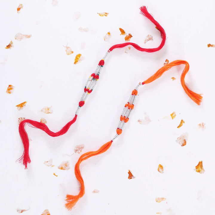 Handmade Beaded Jaali Zari Rakhi With Roli Chawal Set Of 2 - Laying Flat on Decorative Surface