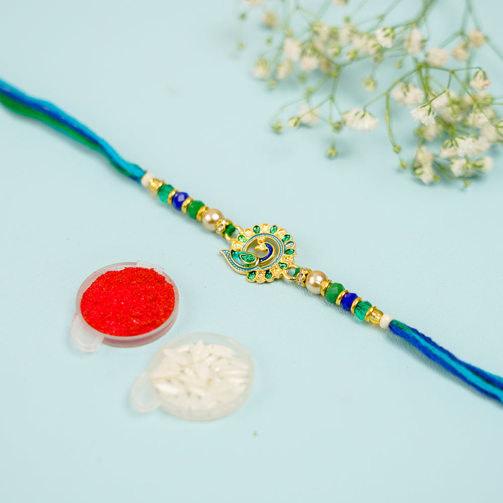 Handmade Blue And Green Peacock Jadtar Rakhi With Roli Chawal - Front View with Accessories Showcase