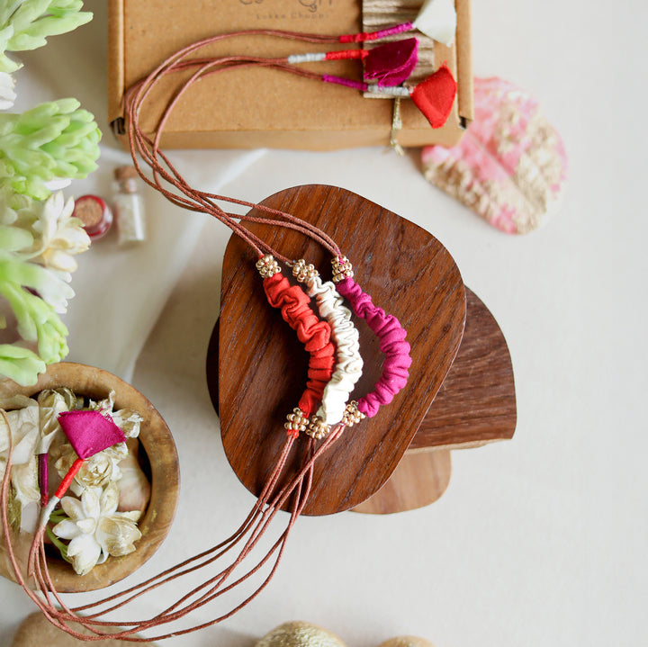 Handmade Reusable Beaded Ruched Upcycled Fabric Rakhi With Roli Chawal For Brother Set Of 3 - Top view with surrounding decor