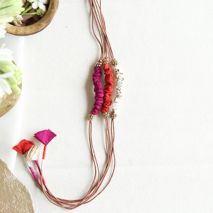 Handmade Reusable Beaded Ruched Upcycled Fabric Rakhi With Roli Chawal For Brother Set Of 3 - Flat lay of bracelets on white fabric
