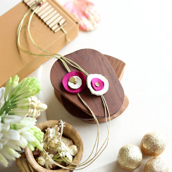 Handmade Reusable Floral And Gold Accent Upcycled Fabric Rakhi With Roli Chawal For Brother Set Of 2 - Styled on wooden display