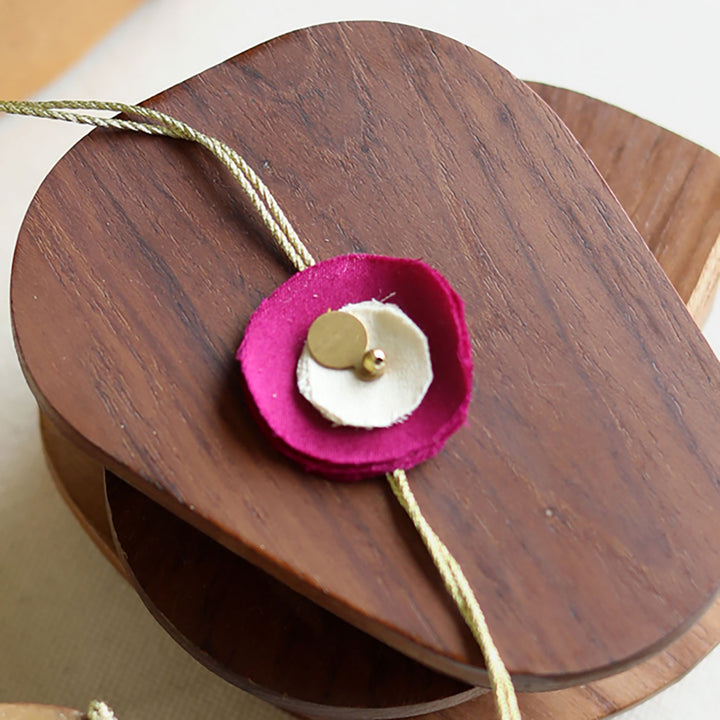 Handmade Reusable Floral And Gold Accent Upcycled Fabric Rakhi With Roli Chawal For Brother - Single flower detail on wooden spool