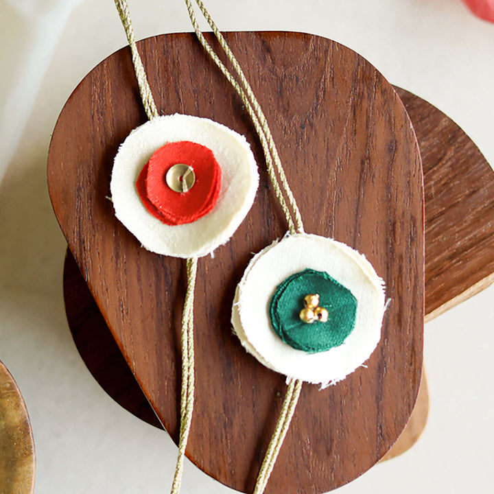 Handmade Reusable Dual Layer Upcycled Fabric Rakhi With Roli Chawal For Brother Set Of 2 - Close-up of Green and Orange Flowers
